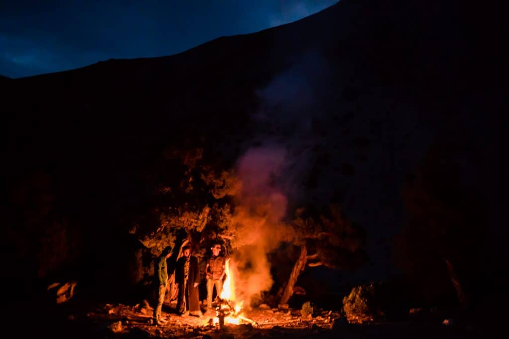 Kulikalon camping group of three men standing beside a campfire at night