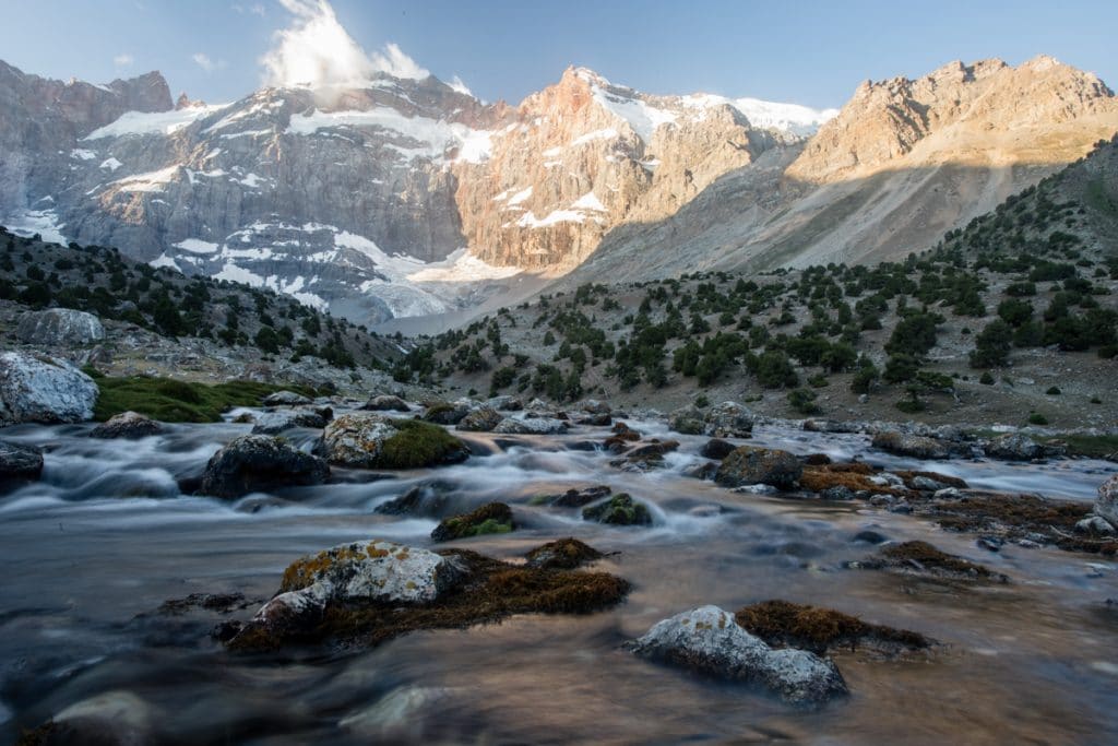 Mountain stream in front of tall rocky peaks with snow cover