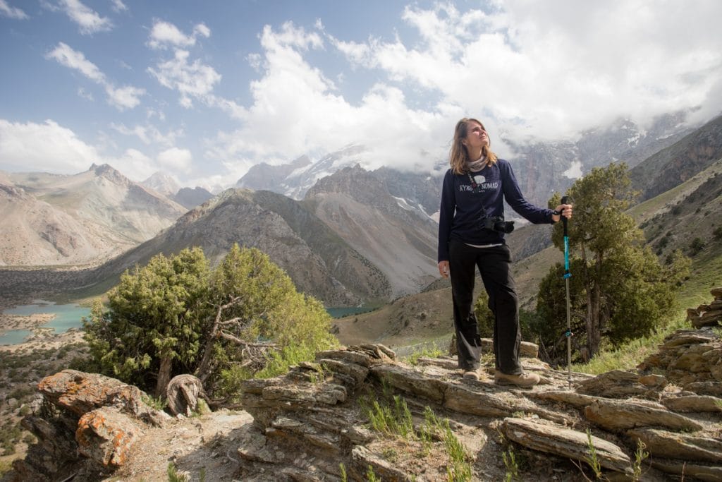 Woman posing on mountain pass with steep rocky mountains in background